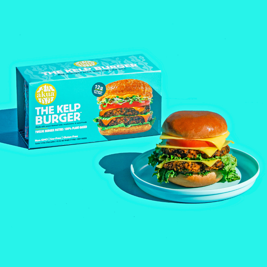 Stacked Kelp burger with multiple patties, cheese, veg and buns, next to its box