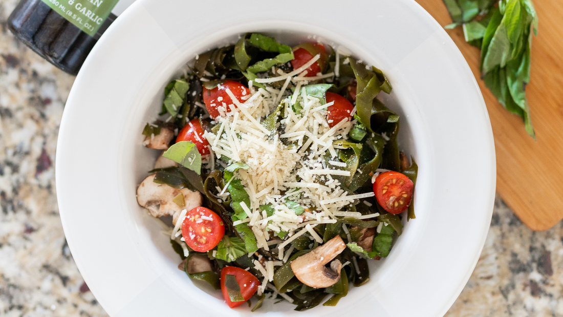 Top-down bowl of kelp pasta with mushrooms, tomatoes and cheese