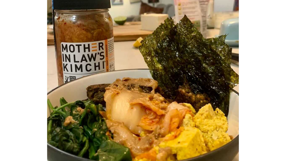 Jar of kimchi with bowl of kimchi with kelp and veg in the foreground