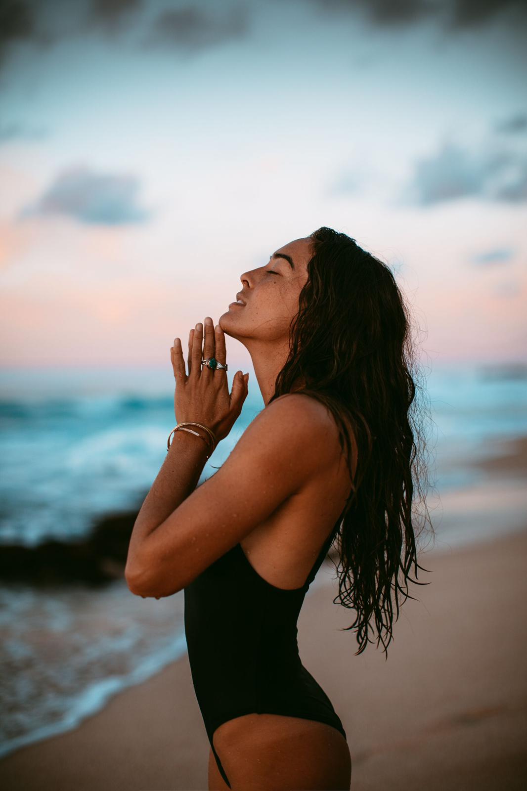 Chelsea Yamase on a beach looking like she's praying to the sky
