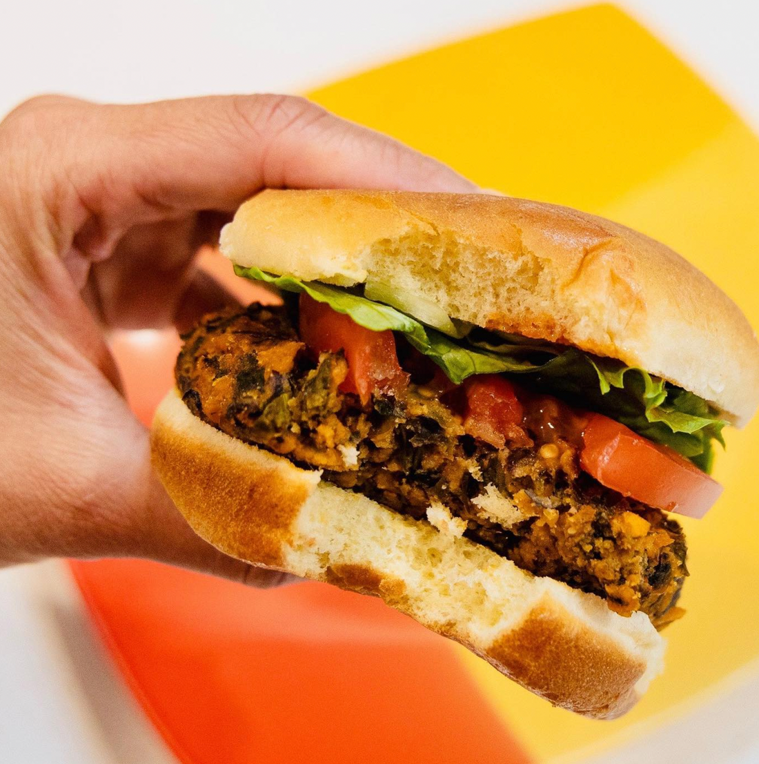 A bite out of a kelp burger with buns, tomatoes and lettuce