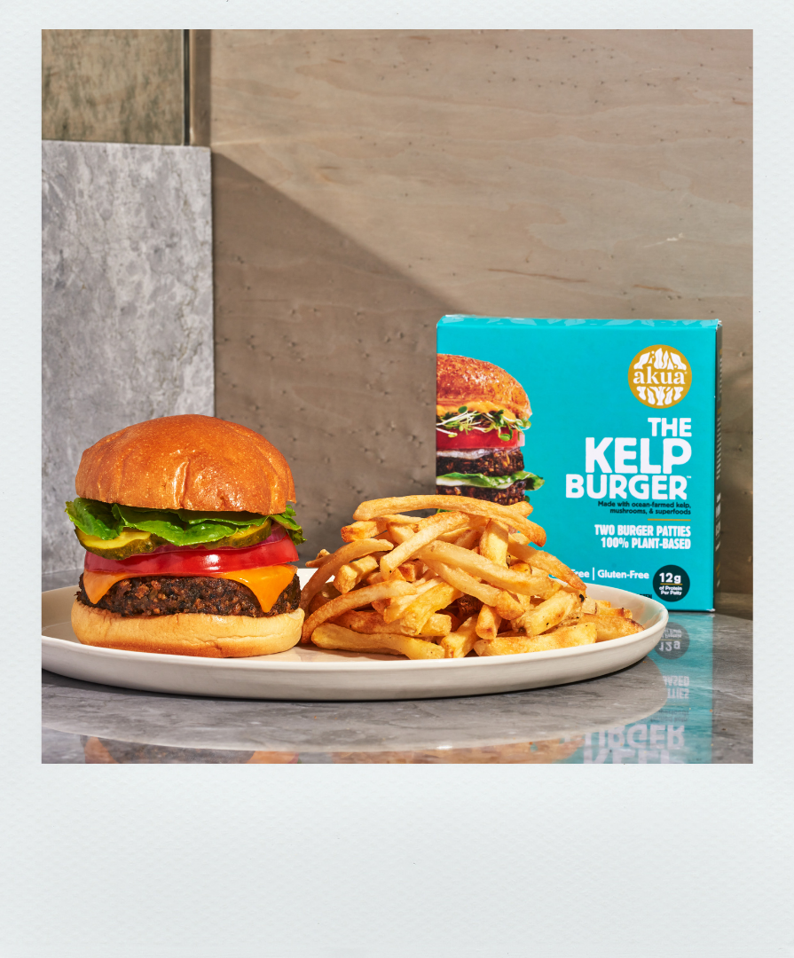 Kelp Burger dressed up sitting next to a plate of fries and a box