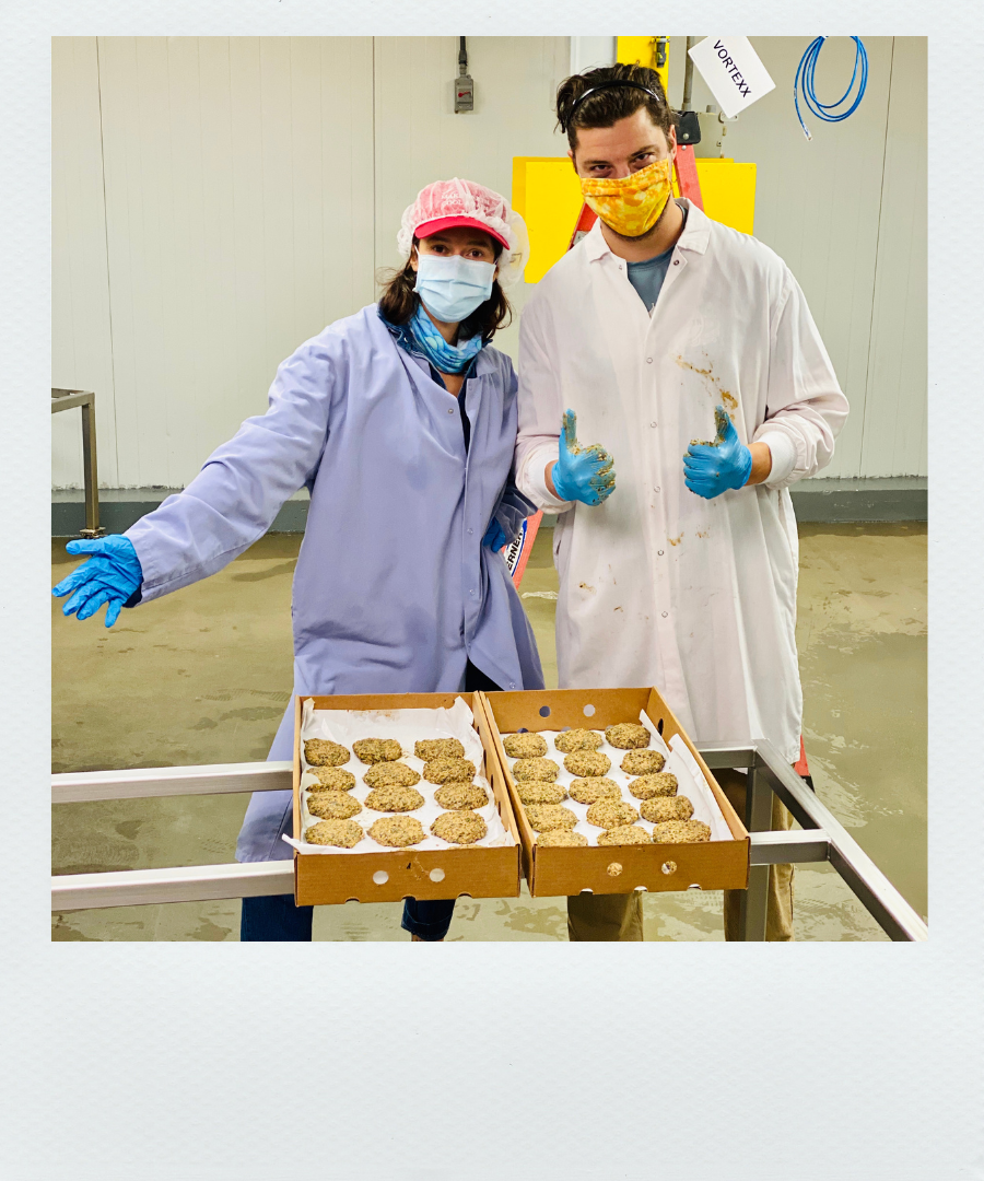 Poloroid-style photo of two people in a production line with boxes of Kelp Krab Cakes and thumbs up